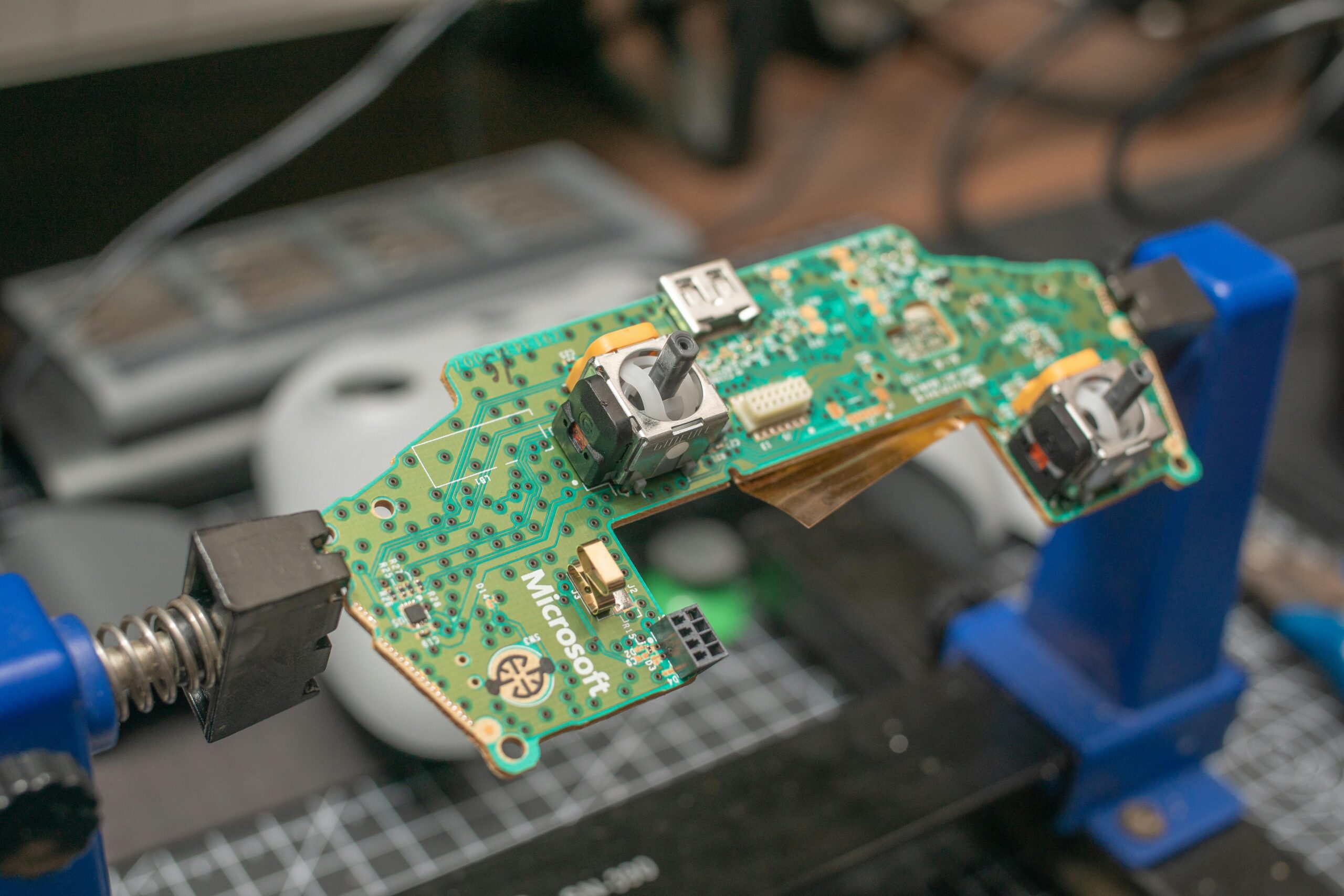 Detailed view of a gaming controller circuit board in repair setup.